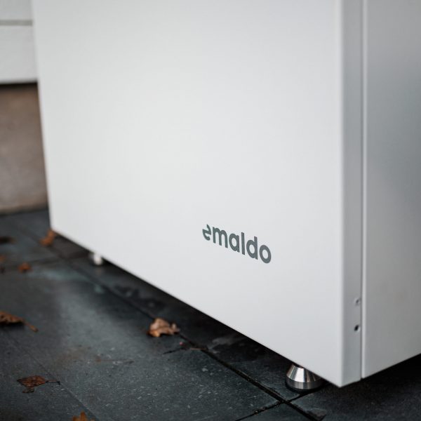 Batterilagring Närbild på Emaldo-batterilagring på hembatteri installerat i Täby – omgiven av höstlöv på stensatt uteplats.